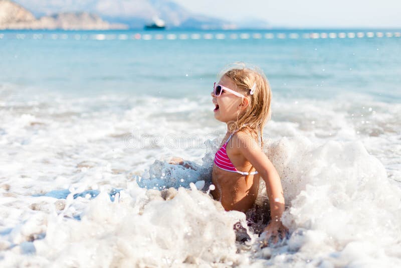 Kid is swimming in waves at sea beach in vacation. Child girl is enjoying summer holiday stock photo Kid is swimming in waves at sea beach in vacation. Child girl is enjoying summer holiday stock photo