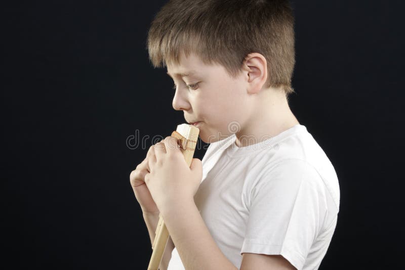 Kid in white playing panflute sideview stock image