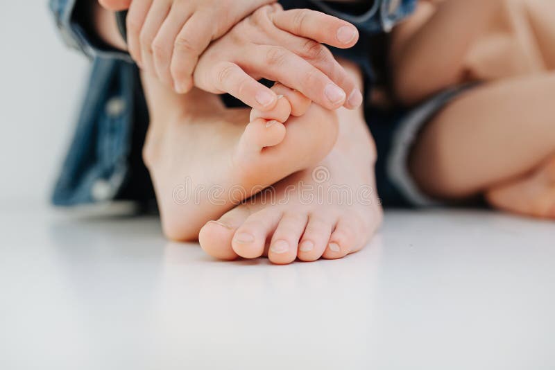 Kid& x27;s hands and feet close up. With slightly overgrown but clean nails.