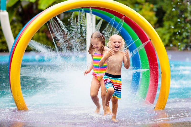 Kids play in aqua park. Children at water playground of tropical amusement park. Little girl and boy at swimming pool. Child playing at water slide on summer vacation in Asia. Swim wear for young kid. Kids play in aqua park. Children at water playground of tropical amusement park. Little girl and boy at swimming pool. Child playing at water slide on summer vacation in Asia. Swim wear for young kid