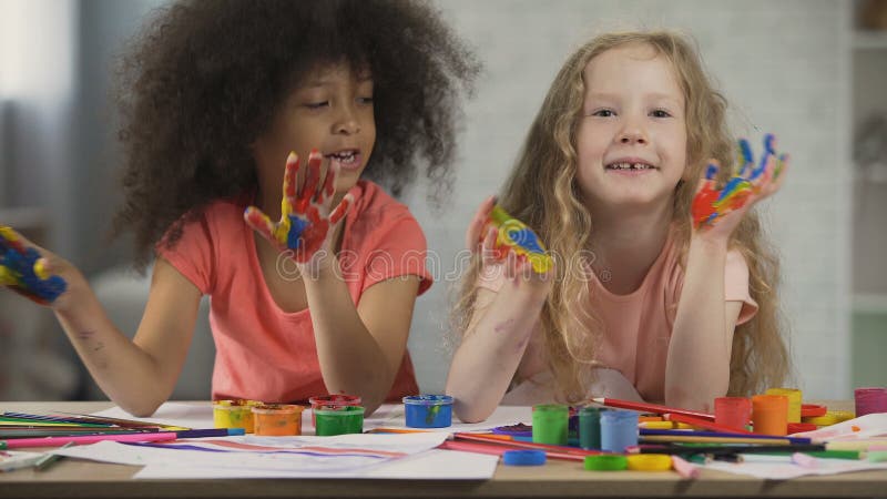 Kids art club. Multiracial children waving painted palms and singing, childhood