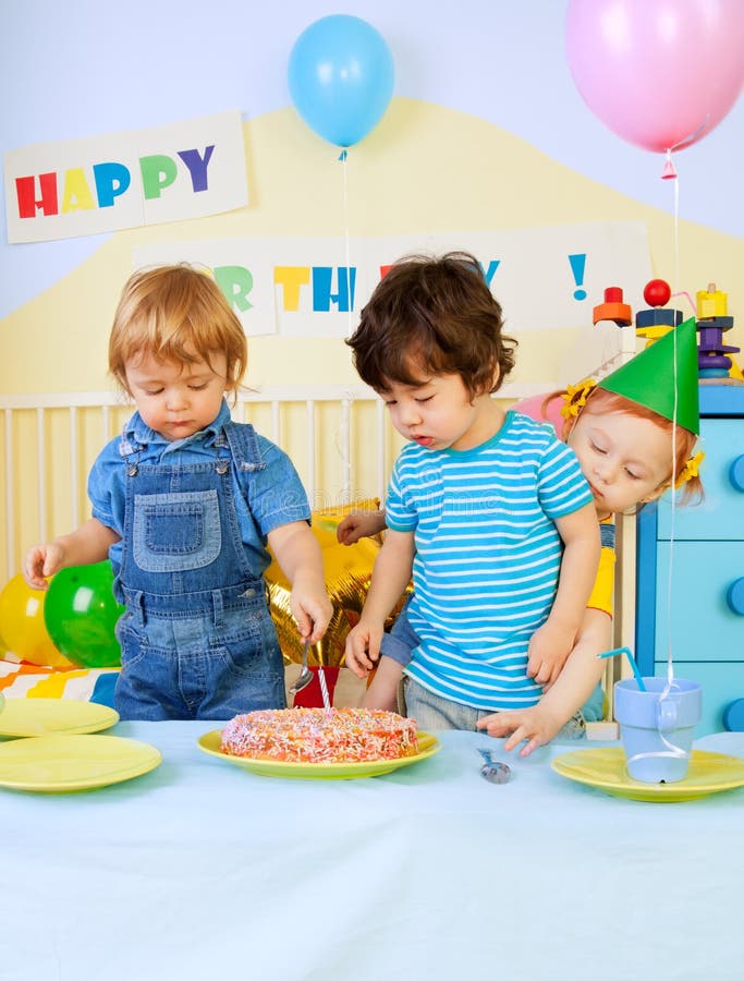 Kids and birthday cake. Kids around birthday cake on birthday party - two boys and girl royalty free stock photos Kids and birthday cake. Kids around birthday cake on birthday party - two boys and girl royalty free stock photos