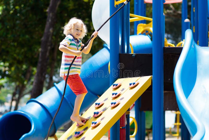 Kids climbing and sliding on outdoor playground. Children play in sunny summer park. Activity and amusement center in kindergarten or school yard. Child on colorful slide. Toddler kid outdoors. Kids climbing and sliding on outdoor playground. Children play in sunny summer park. Activity and amusement center in kindergarten or school yard. Child on colorful slide. Toddler kid outdoors.