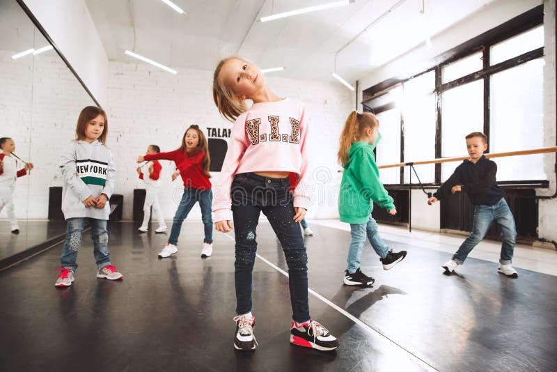 The kids at dance school. Ballet, hiphop, street, funky and modern dancers over studio background. Children showing aerobic element. Teens in hip hop style. Sport, fitness and lifestyle concept.