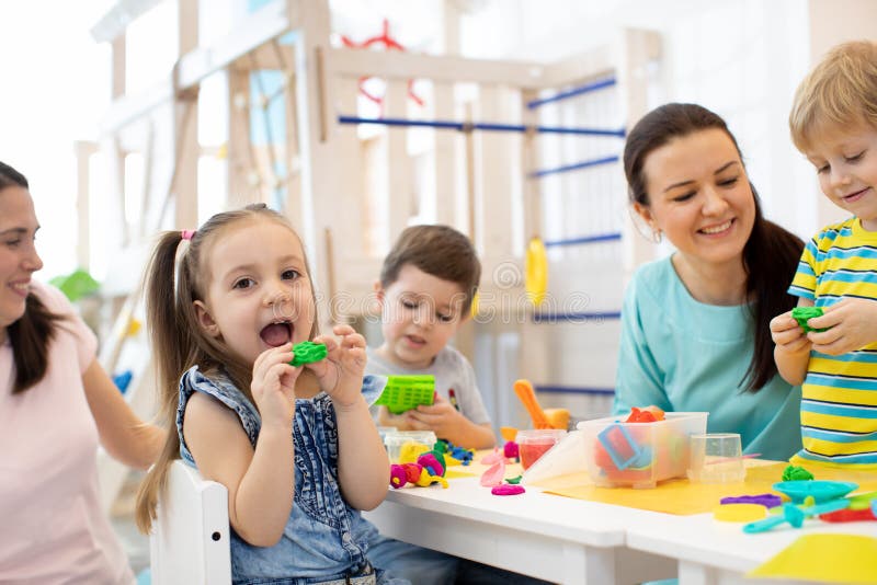 Kids dough play in daycare centre. Children mold from plasticine in kindergarten. Little students knead modeling clay with hands