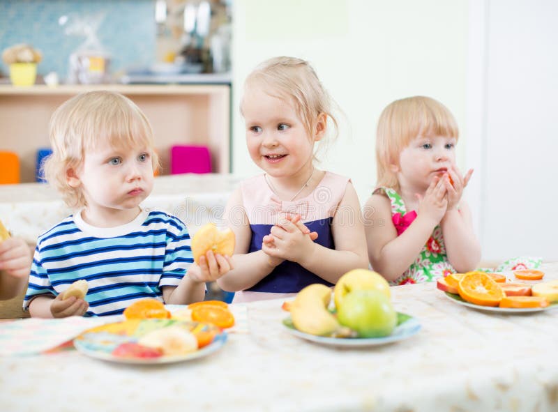 Kids eating fruits in kindergarten dinning room