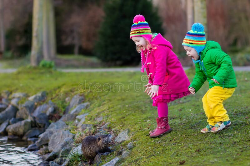 Kids feeding otter in autumn park