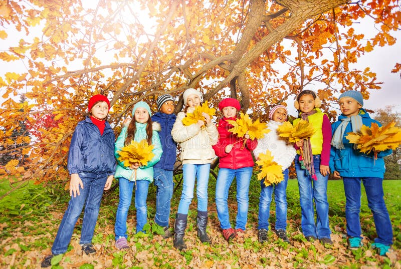 Kids group with bunches of yellow maple leaves
