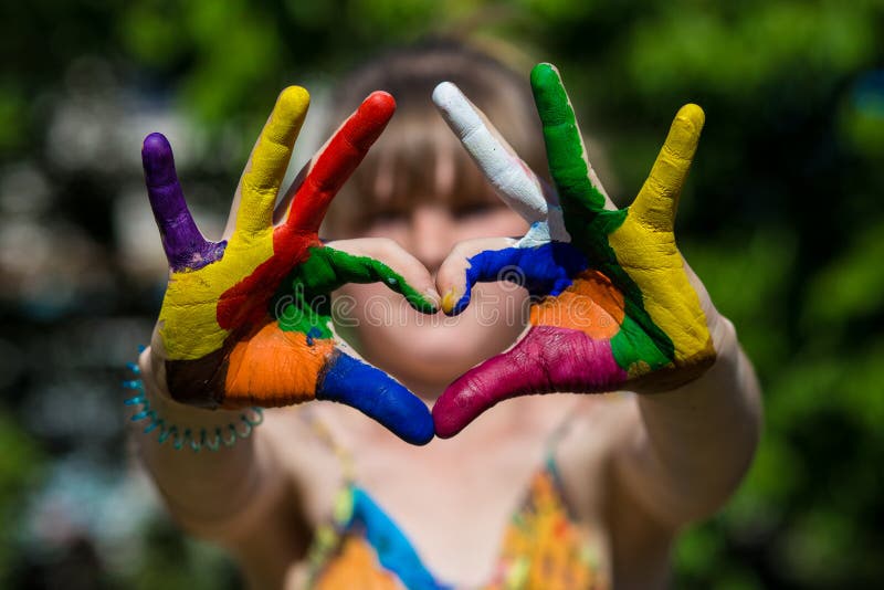 Kids hands in color paints make a heart shape, focus on hands