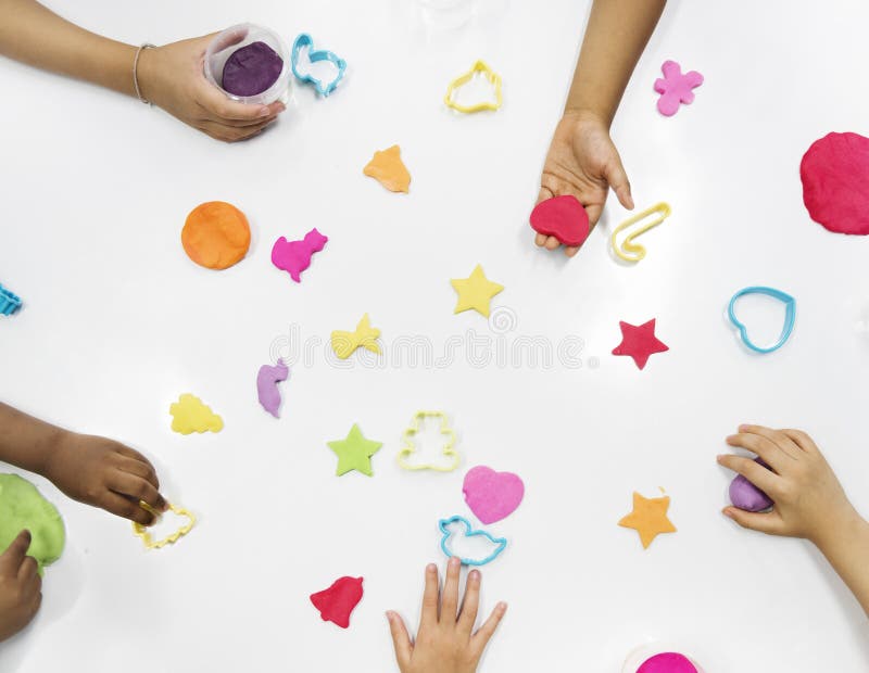 Kids hands with colorful clays on white table