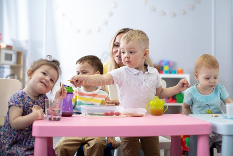Kids have a dinner in kindergarten. Little boys and girls from the group of children sitting at the table with lunch and royalty free stock images Kids have a dinner in kindergarten. Little boys and girls from the group of children sitting at the table with lunch and royalty free stock images