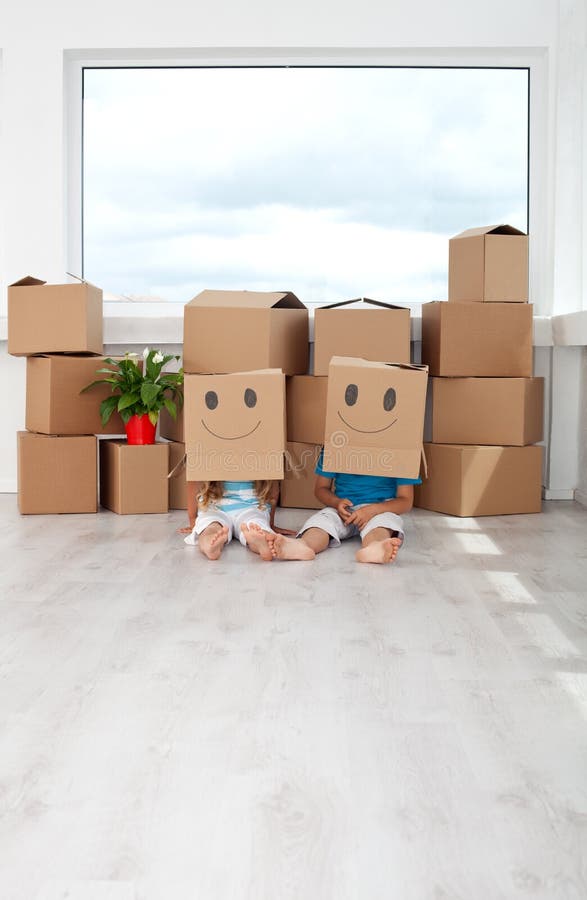 Kids having fun in their new home playing with cardboard boxes