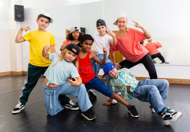 Positive girls and boys with female teacher posing in dance studio during hip hop class. Positive girls and boys with female teacher posing in dance studio during hip hop class