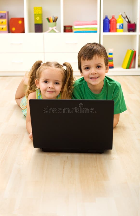 Kids with laptop laying on the floor at home in their room