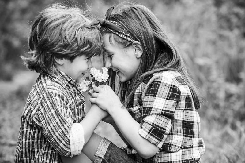 Kids Love Concept. The Real History of Valentines Day. Valentines Day Cards. Little friends blowing dandelion seeds. Together in a park royalty free stock photo Kids Love Concept. The Real History of Valentines Day. Valentines Day Cards. Little friends blowing dandelion seeds. Together in a park royalty free stock photo
