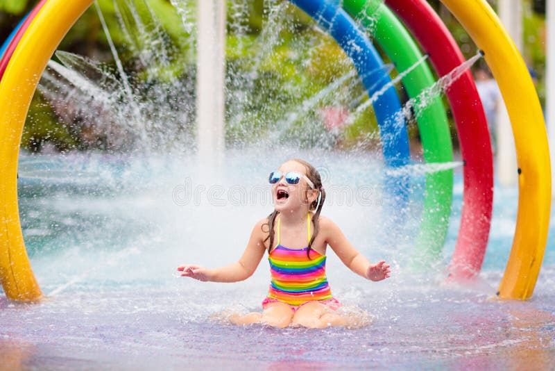 Kids play in aqua park. Children at water playground of tropical amusement park. Little girl at swimming pool. Child playing at water slide on summer vacation in Asia. Swim wear for young kid. Kids play in aqua park. Children at water playground of tropical amusement park. Little girl at swimming pool. Child playing at water slide on summer vacation in Asia. Swim wear for young kid