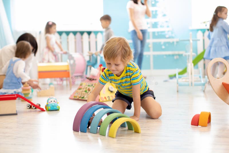 Kids play on floor with educational toys. Toys for preschool and kindergarten. Children in nursery or daycare