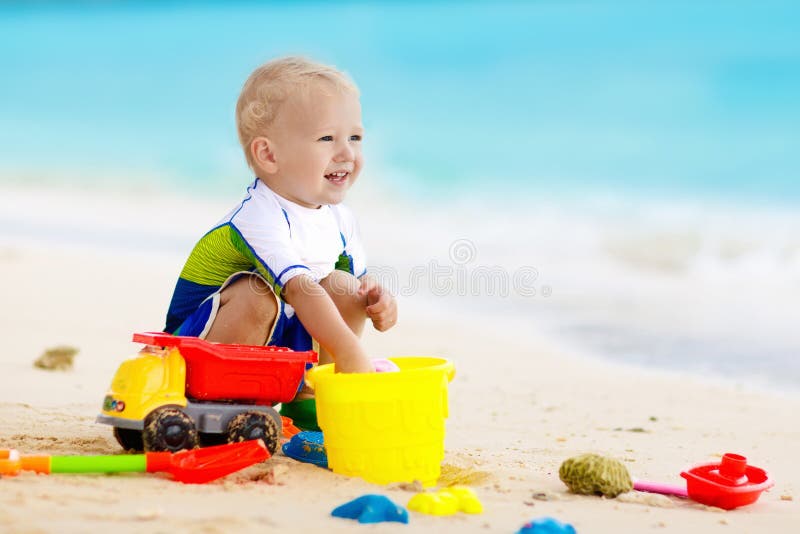 Kids play on tropical beach. Sand and water toy.