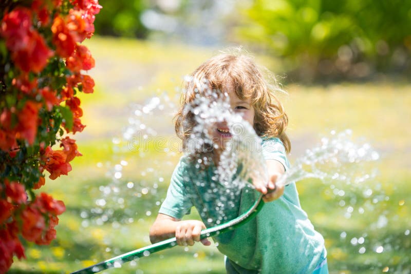 Kids play with water garden hose in yard. Outdoor children summer fun. Little boy playing with water hose in backyard. Party game for children. Healthy
