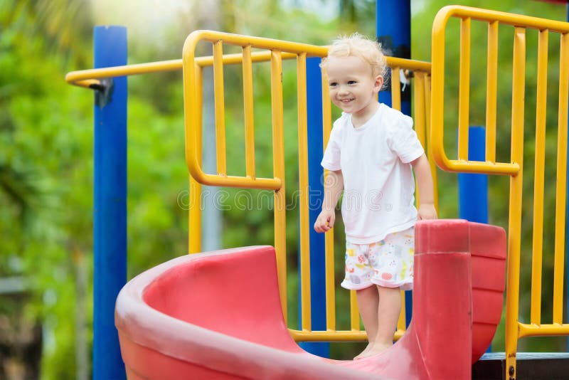 Kids climbing and sliding on outdoor playground. Children play in sunny summer park. Activity and amusement center in kindergarten or school yard. Child on colorful slide. Toddler kid outdoors. Kids climbing and sliding on outdoor playground. Children play in sunny summer park. Activity and amusement center in kindergarten or school yard. Child on colorful slide. Toddler kid outdoors.