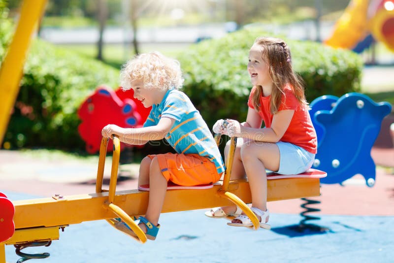 Kids climbing and sliding on outdoor playground. Children play in sunny summer park. Activity and amusement center in kindergarten or school yard. Child on colorful swing. Toddler kid outdoors. Kids climbing and sliding on outdoor playground. Children play in sunny summer park. Activity and amusement center in kindergarten or school yard. Child on colorful swing. Toddler kid outdoors.