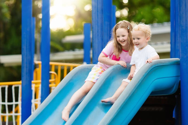 Kids climbing and sliding on outdoor playground. Children play in sunny summer park. Activity and amusement center in kindergarten or school yard. Child on colorful slide. Toddler kid outdoors. Kids climbing and sliding on outdoor playground. Children play in sunny summer park. Activity and amusement center in kindergarten or school yard. Child on colorful slide. Toddler kid outdoors.