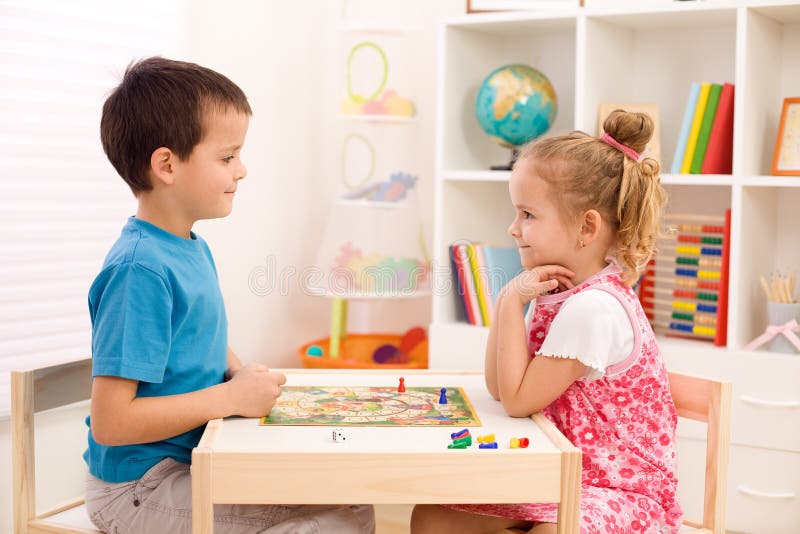 Little boy and girl playing board game in their room sitting at the table. Little boy and girl playing board game in their room sitting at the table