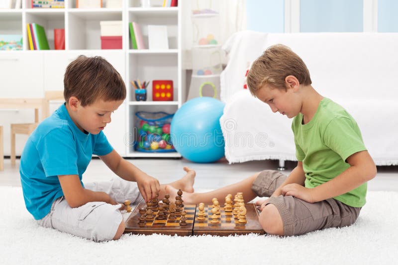 Kids playing chess sitting on the floor in their room. Kids playing chess sitting on the floor in their room