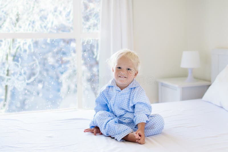 Kid in bed. Winter window. Child at home by snow.