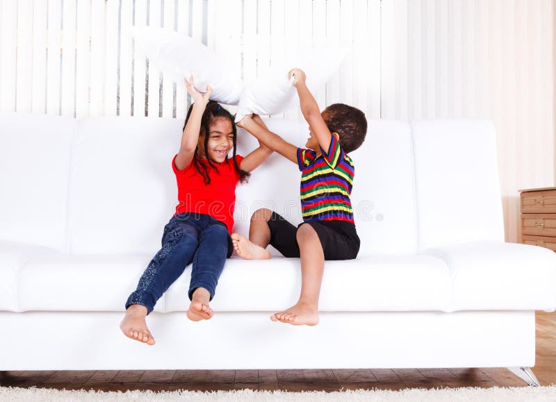 Two african american kids playing with pillows
