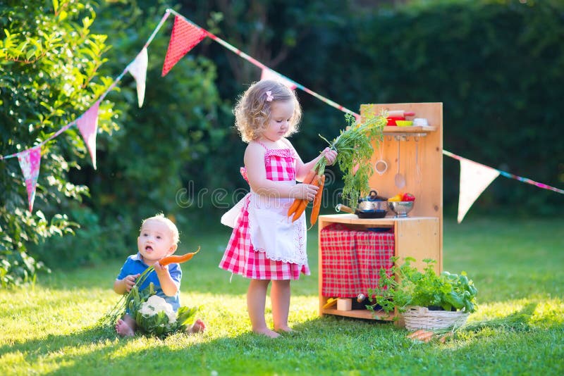 Kids playing with a toy kitchen in a summer garden