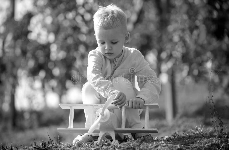 Kids playing with vintage wooden airplane outdoors. Kids having fun with toy airplane in field against nature background royalty free stock images