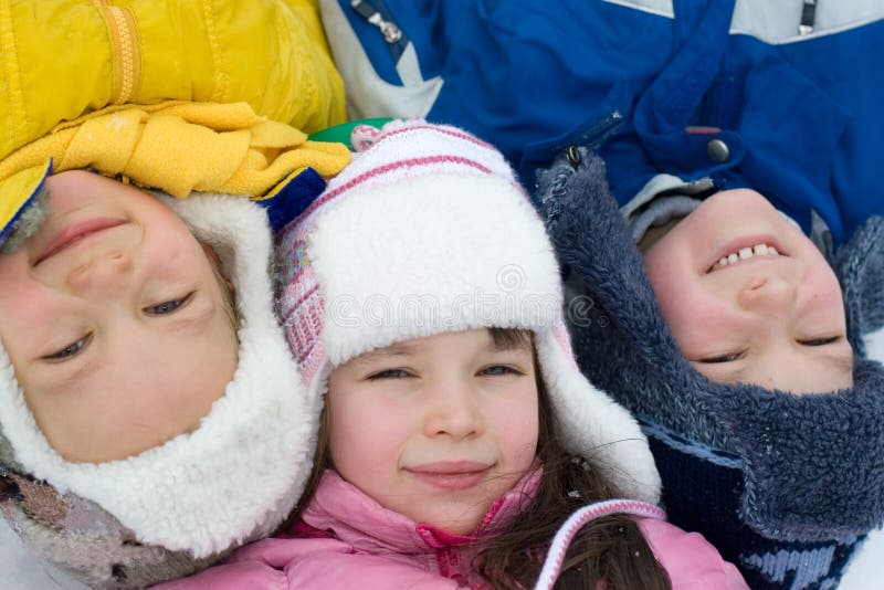 Tre bambini, giaceva sulla neve, in una fredda giornata d'inverno, per questa foto divertente.