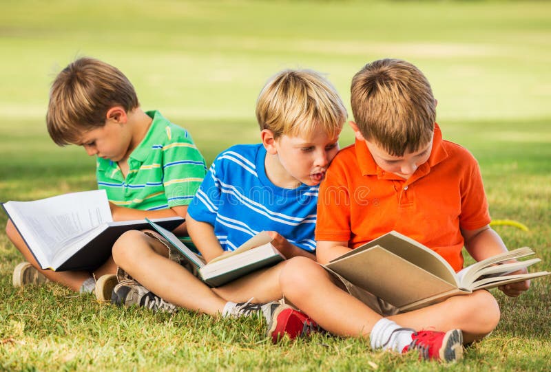 Gruppo di Bambini Felici di Leggere i Libri al di Fuori, l'Amicizia e il Concetto di Apprendimento.