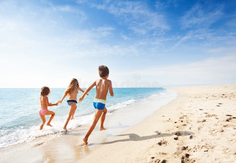 Kids running along beach during summer vacation