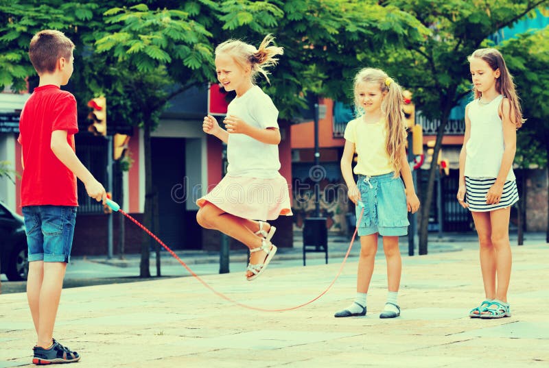 Happy kids in school age playing together with jumping rope outdoors