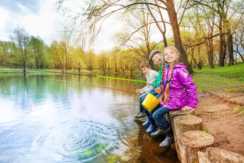 Kids sitting near pond holding fishing tackles