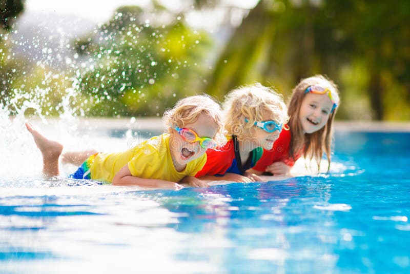 Kids in swimming pool. Children swim. Family fun. Kids play in swimming pool. Children learn to swim in outdoor pool of tropical resort during family summer