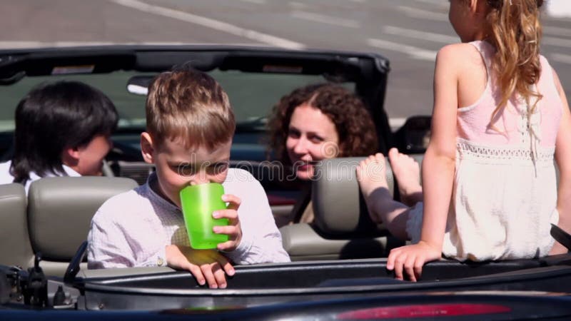 Kids with their parents sit in cabriolet and boy stock footage