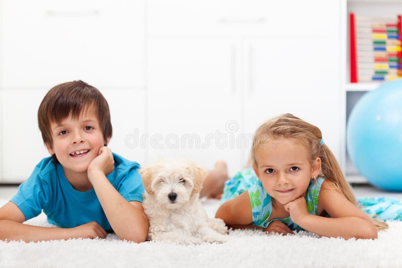 Happy kids with their pet - a fluffy dog - laying on the floor