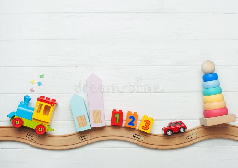 Kids toys on toy wooden railway on white wooden background