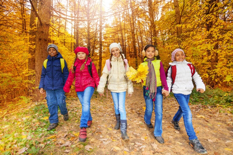 Kids with yellow maple leaves bunch walk in forest