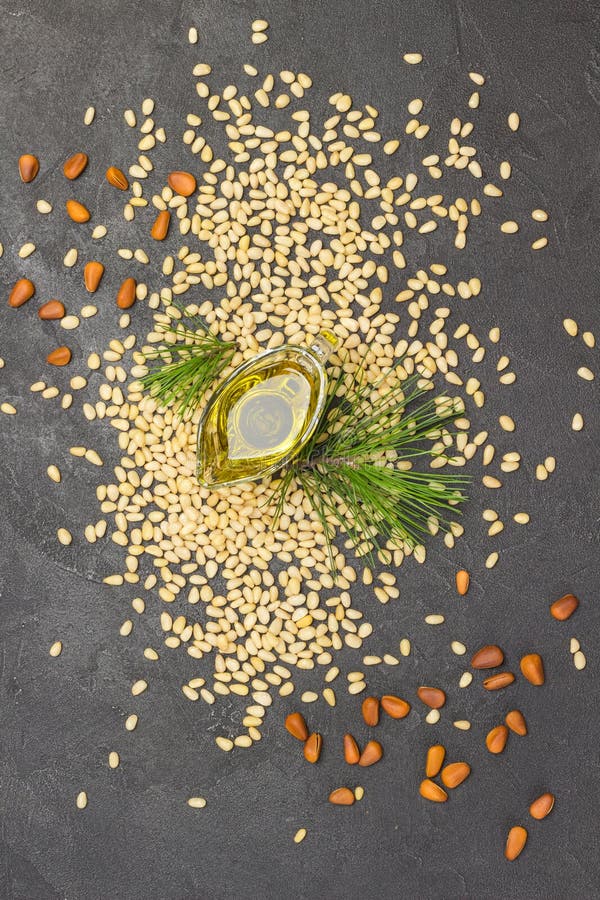 Pine nuts, pine nut oil and cedar branch. Black background. Flat lay. Pine nuts, pine nut oil and cedar branch. Black background. Flat lay