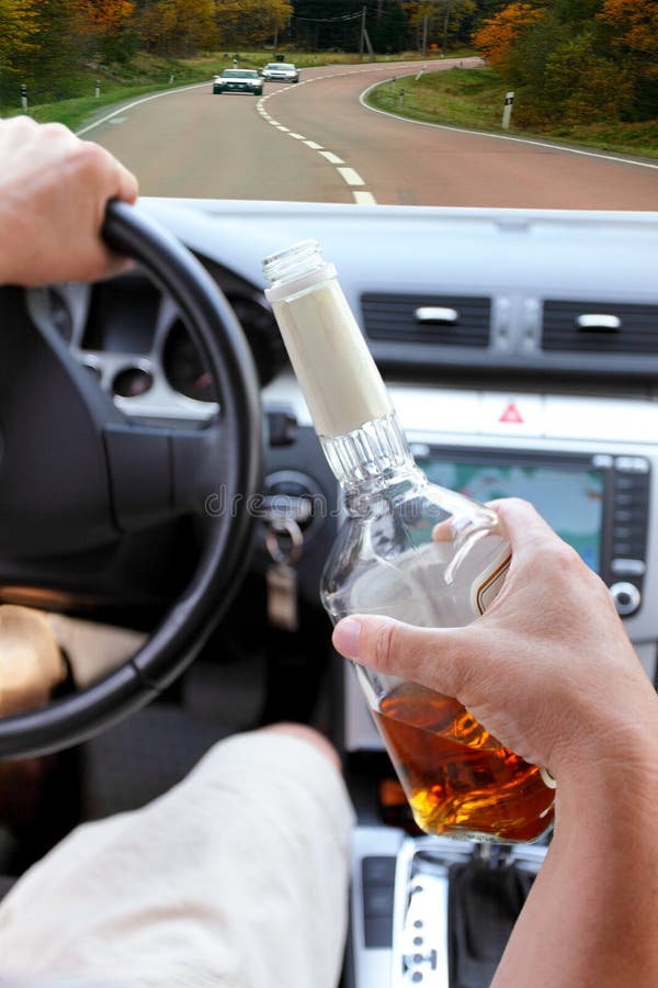 drunk driver on a forest road with a bottle of alcohol in hand. drunk driver on a forest road with a bottle of alcohol in hand