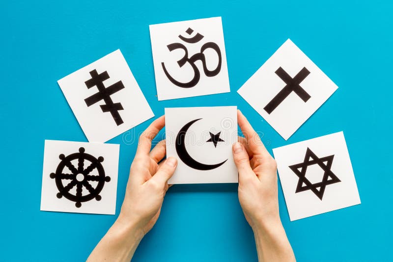 Kies het religie concept. hand met islam - recente religieuze symbolen in de buurt van de wereld op blauwe achtergrond bovenaanzic