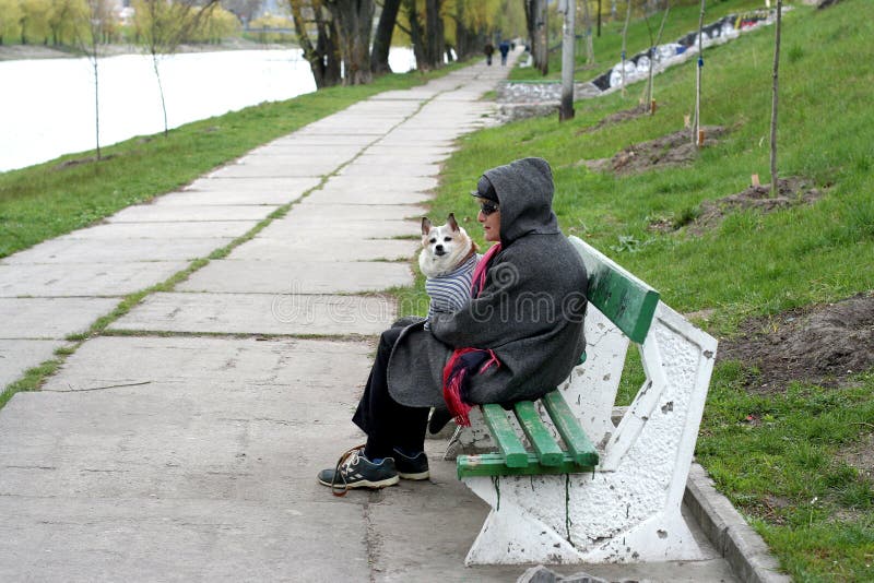 kiev l'ucraina 21 04 2007 Una donna sta sedendosi sul banco e sta tenendo un cane sulle sue mani fotografia stock kiev l'ucraina 21 04 2007 Una donna sta sedendosi sul banco e sta tenendo un cane sulle sue mani fotografia stock