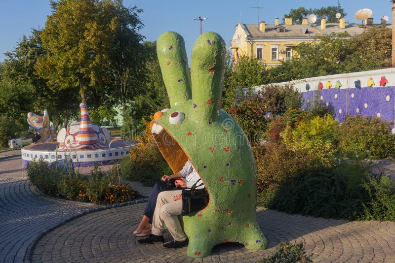 Kiev, Ukraine - September 17, 2015: Couple sitting on a bench in a fantastic character royalty free stock images Kiev, Ukraine - September 17, 2015: Couple sitting on a bench in a fantastic character royalty free stock images