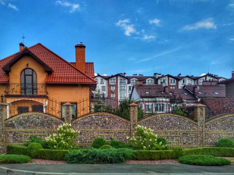 KIEV, UKRAINE - 25 september 2019: Ett vackert privat hus med en gräs och ett vackert staket mot en blå himmel royaltyfria foton KIEV, UKRAINE - 25 september 2019: Ett vackert privat hus med en gräs och ett vackert staket mot en blå himmel royaltyfria foton