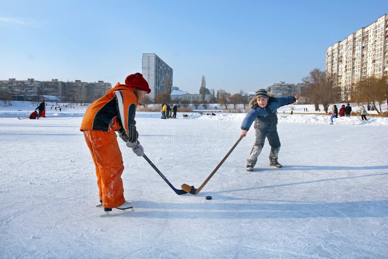Kiev, Ukraine, 19.02.2012 Two children on a rink with hockey sticks and a washer play hockey stock photography Kiev, Ukraine, 19.02.2012 Two children on a rink with hockey sticks and a washer play hockey stock photography