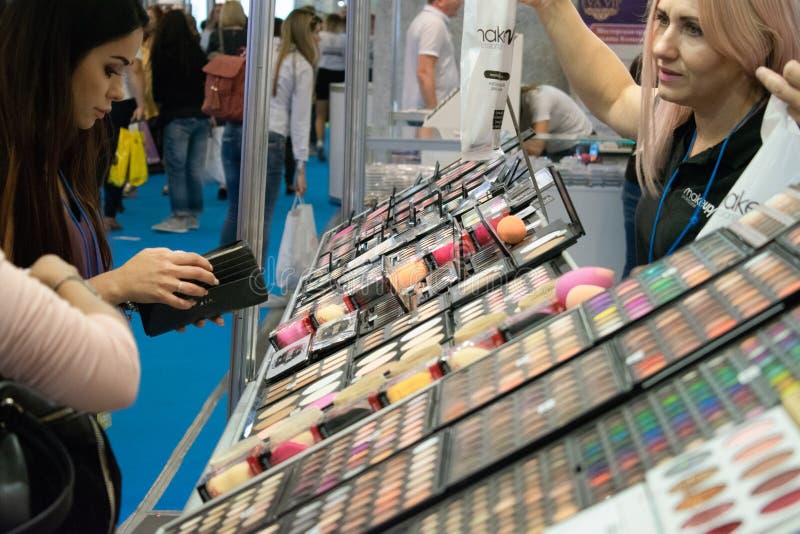 Kiev, Ukraine  19 September, 2018: Young woman chooses decorative cosmetics at the beauty store stand during beauty show. Girl